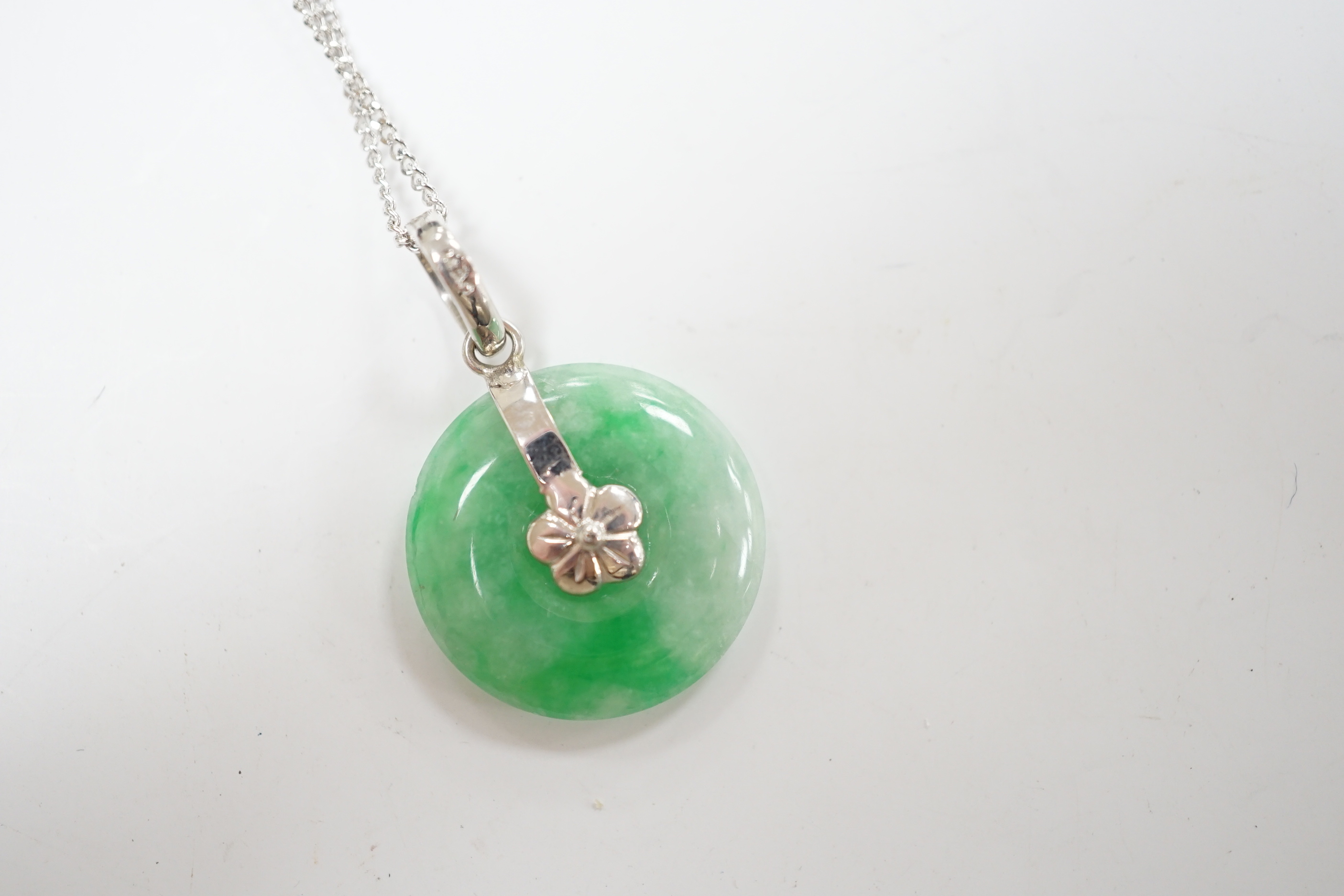 A modern 14k white metal and jade set disc pendant, 18mm, on a 9ct white gold chain, 42cm, gross weight 4.3 grams.